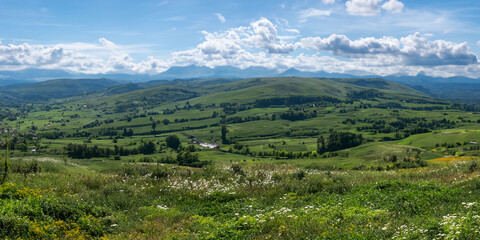 Naklejka premium Scenic view of rolling green hills and cloudy blue sky in countryside landscape