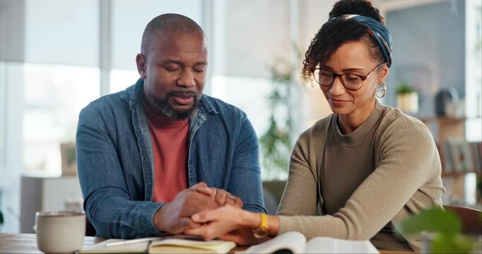 Religion, couple and bible by man and woman holding hands and praying for peace, worship or faith with coffee. Family, God and people with prayer, christianity or Jesus Christ praise together in home