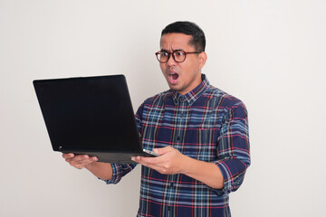A man looking at his laptop with shocked expression