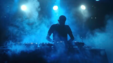 Silhouette of DJ mixing music with smoke and light.