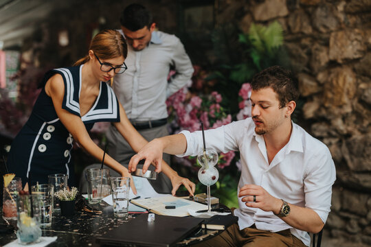A group of professionals engage in a collaborative discussion at an outdoor cafe. They are reviewing documents and enjoying beverages, creating a relaxed business environment.