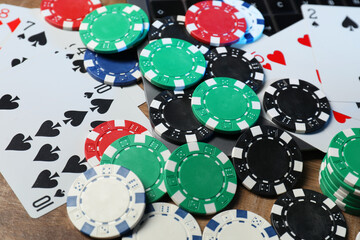 Poker chips, laptop and playing cards on wooden table, closeup. Online game