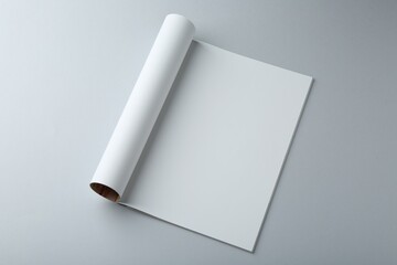 Open magazine with blank page on grey background, above view. Mockup for design