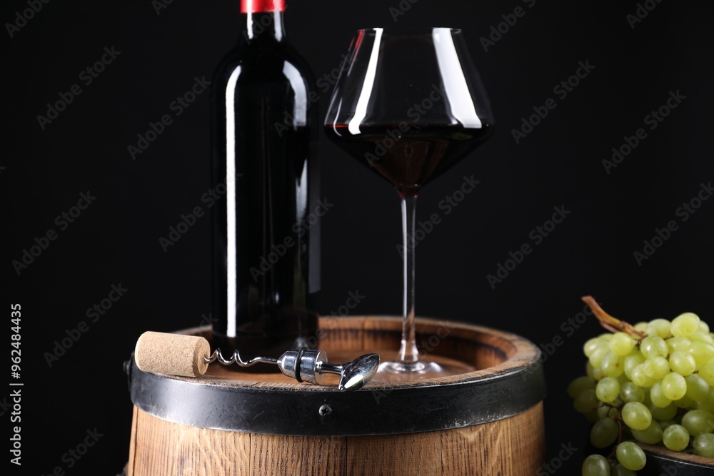 Poster Corkscrew with metal handle, bottle of wine, glass, grapes and wooden barrel against black background