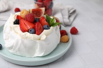 Pavlova cake (meringue dessert) with whipped cream, fresh berries, mint and fig on white tiled table, closeup