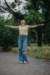 Fototapeta premium A carefree young woman in a yellow shirt and ripped jeans having fun alone in a tranquil park setting.