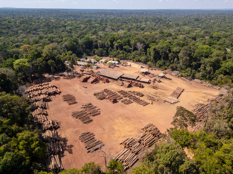 Aerial drone view of Amazon rainforest logging company base: Logging yard, employee housing, equipment and operations nestled, amidst the dense jungle canopy