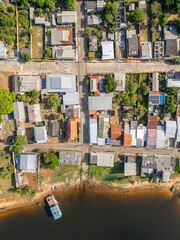 Aerial view, captured by a drone from a perpendicular perspective, of a residential area of a brazilian city situated along the banks of a river in Amazon region