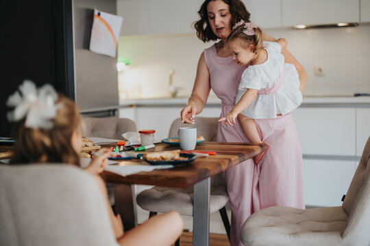 Mother with her young daughters enjoying breakfast together in the kitchen. Family bonding, love, and morning routine