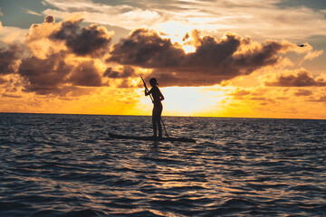 Paddleboarding over the sunset ocean
