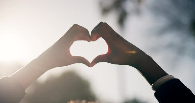 Hands, heart and person with love symbol in nature, garden or adventure for vacation or trip. Sunset, romance and hand romantic gesture with shape emoji park, forest or woods environment on holiday