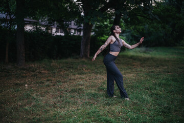 Fototapeta premium A young woman practices yoga poses in a tranquil outdoor setting surrounded by trees, conveying a sense of peace and mindfulness.