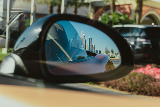 City skyline reflected in side mirror of a car