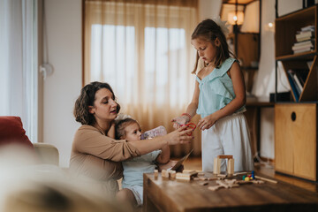 A mother engages with her two daughters, fostering creativity and learning through play. The girls are focused on building structures with wooden blocks in a cozy living room setting.
