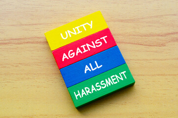 Top view of Unity Against All Harassment text on multicolored wooden blocks. Against discrimination...