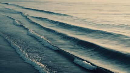 A shot of ocean waves forming parallel lines as they roll towards the shore, captured in soft early morning light