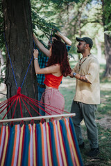 Group of friends setting up a hammock between trees in a forest, enjoying nature and friendship on a sunny day