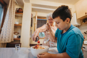 A young boy and his grandmother preparing a meal together in a warm, inviting kitchen. The scene captures family bonding and the joy of cooking.