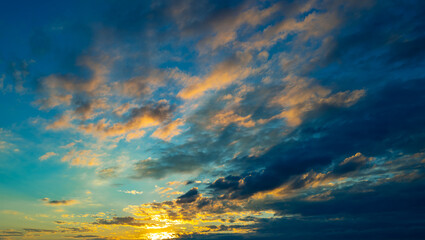 Tropical sunset. Beautiful sunset sky with clouds. Sky blue and orange light of the sun through the clouds in sky. Background of dark clouds before storm. Dramatic clouds. Apocalyptic sky, dark cloud.