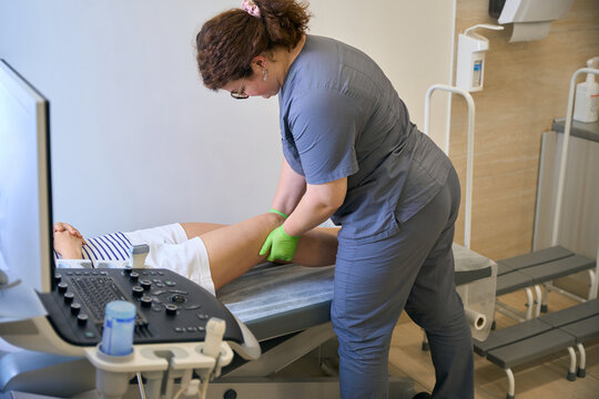Woman in medical uniform examines popliteal lymph nodes of patient