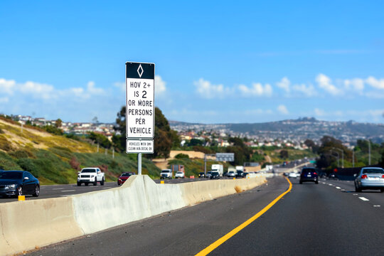 HOV lane road sign on a busy highway specifies that vehicles must have at least two occupants. Selective focus
