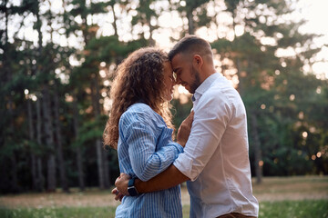 Fototapeta premium Young loving couple standing face to face in nature at sunset.