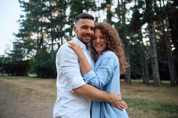 Portrait of happy engaged couple in nature looking at camera.