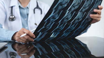 Orthopedics surgeon doctor examining patient's knee joint x-ray films, MRI bone, ct scan in at...