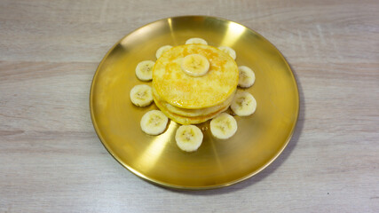 Tasty pancakes with honey, butter and banana on table.