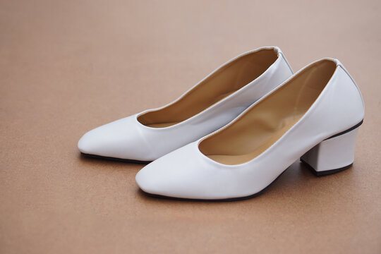 Pair iof white shoes on brown background. Concept, fashion, formal and polite footwears for office workers or nurses to wear shoes in office or hospital to match with white uniform. Footwears.        