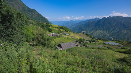 Landscape with green and yellow rice terraced fields , a village and cloudy sky in North Vietnam