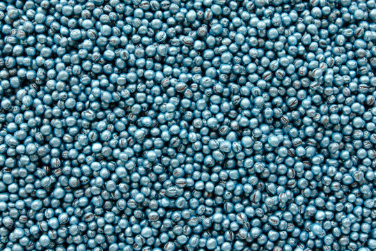 Treated rapeseed with blue coating, background, texture, top view. Encrusted rapeseed ready for sowing. Background of treated rapeseed, blue color, texture, top view.