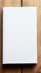 A blank, white, closed book on a wooden table top.