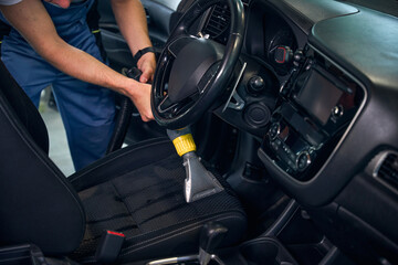 Master cleans front seat of car with special vacuum cleaner