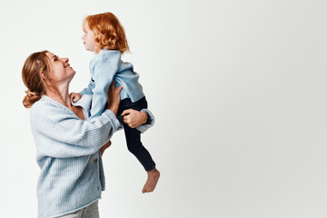 Mother and daughter joyfully playing together on a white background, happy family moment captured in midair joy