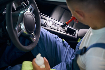 Specialist in a blue overalls performs car detailing