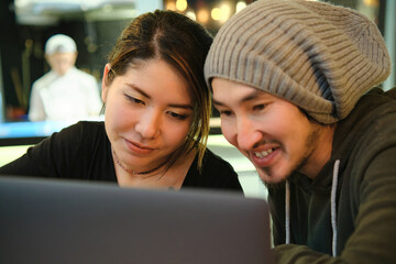 Asian couple sitting at a table in a restaurant and working with