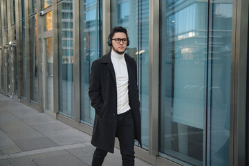 Young man walking in a city with headphones on