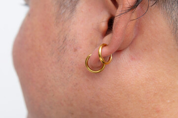 Close up of two gold Clip-on Hoop Earring attached on a man's earlobe. Slide spring style fake ear ring.