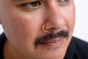 Close up of a gold Clip-on Hoop nose ring attached on a man's nose. Slide spring style fake...