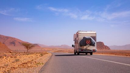 Obraz premium motorhome on asphalt road on arid landscape