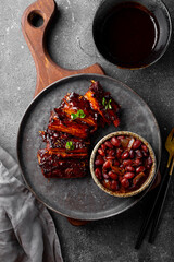 Roasted Pork Ribs in BBQ Sauce with Red Beans in the plate top view vertical photo