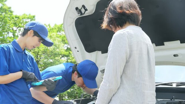 自動車のエンジンルームを点検する作業員