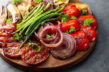 grilled vegetables - eggplant, pepper, onion, tomato and beans on grey background close up