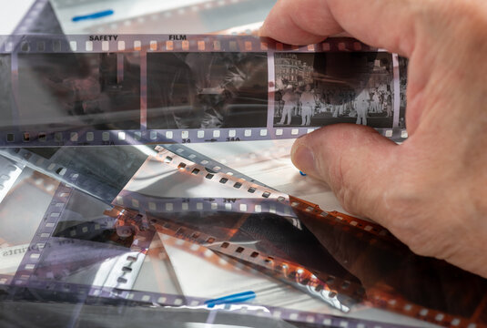 A person holding up a black and white film strip to examine the processing results.