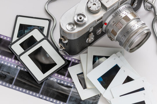 A classic vintage camera with photo filmstrip negatives and slides isolated in white.