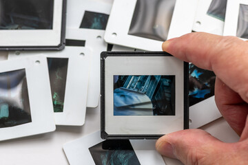 A person holding and examining a colour film slide checking for quality.