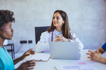 Medical Team Meeting With Confident Female Doctor Discussing Patient Care