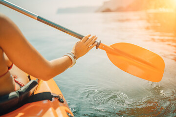 Woman in kayak back view. Happy woman with long hair in a swimsuit and hat floating in kayak on the...