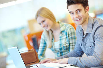Obraz premium Education, laptop and portrait of student man in library at college or university campus for learning. Computer, development and online study with happy person at school desk or table for scholarship